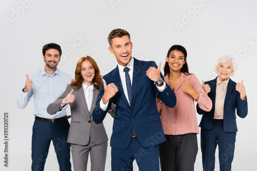 Cheerful multiethnic businesspeople showing like gesture isolated on grey