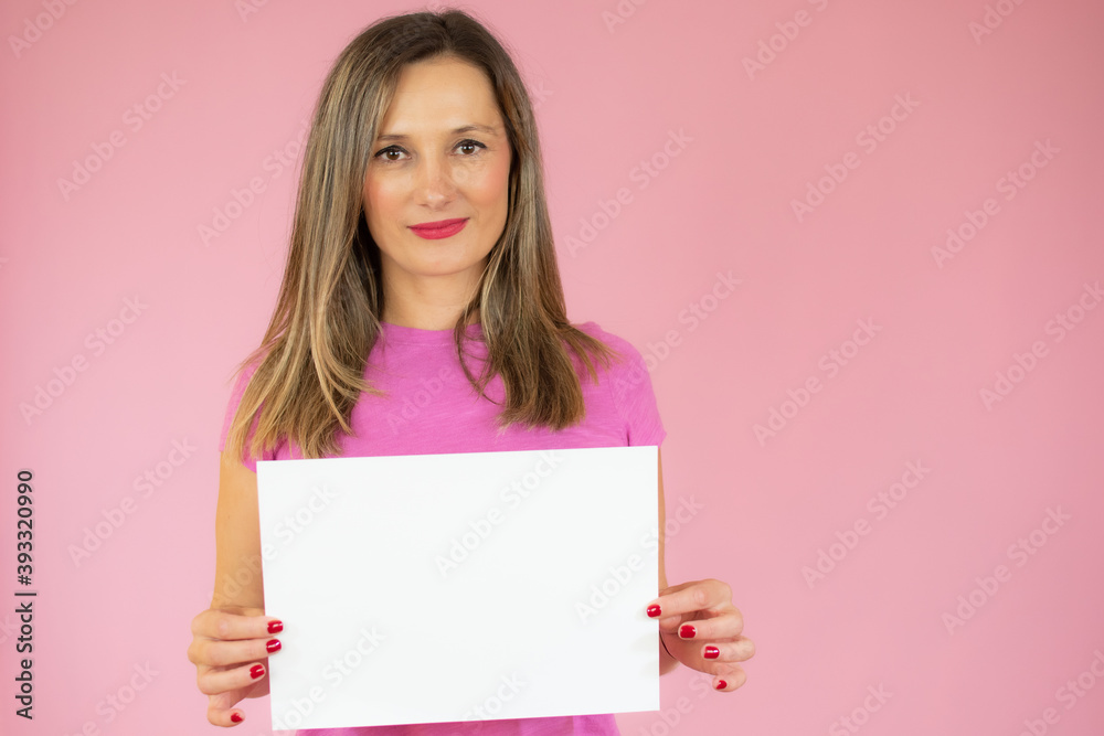 A young woman is showing a piece of paper over pink background A young woman is showing a piece of paper over pink background