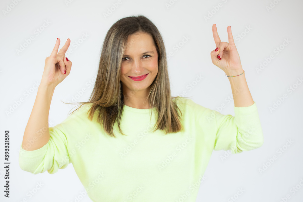 Young woman wearing casual sweater with crazy expression doing rock symbol with hands up. music star. heavy concept. Young woman wearing casual sweater with crazy expression doing rock symbol with hands up. music star. heavy concept.