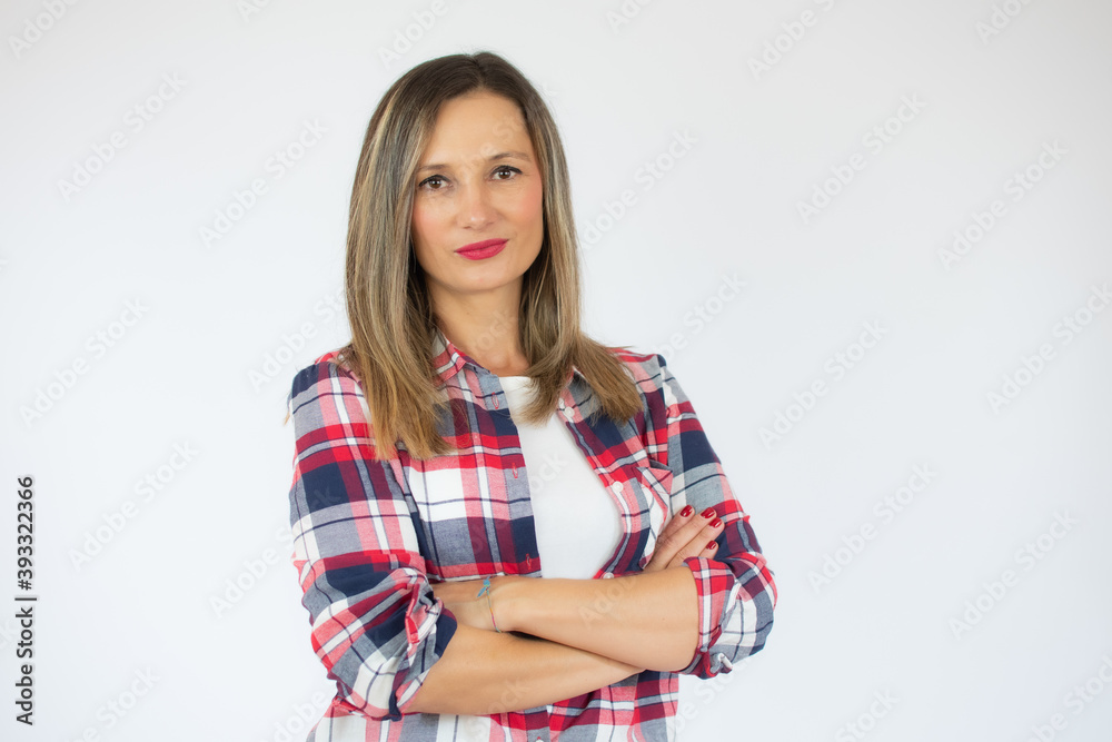 Portrait of a smiling young woman in plaid shirt standing with arms folded isolated over white background Portrait of a smiling young woman in plaid shirt standing with arms folded isolated over white background
