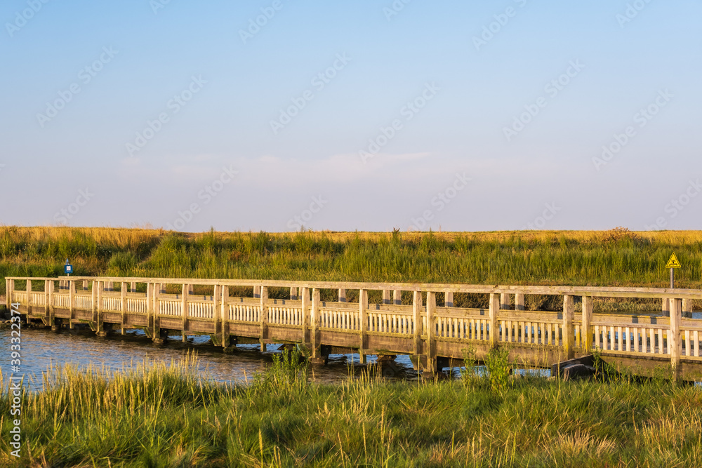 A wooden bridge in Langwarder Groden / Germany on the North Sea in the warm evening light A wooden bridge in Langwarder Groden / Germany on the North Sea in the warm evening light