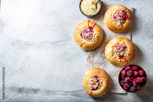 Homemade Sweet Yeast Buns filled with Berry and with crumble. Concrete bsckground.