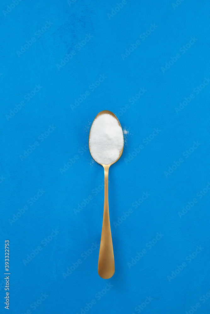 Collagen powder in golden spoon on blue textured background. Place for text Collagen powder in golden spoon on blue textured background. Place for text
