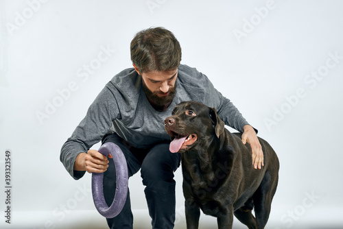 Man with dog training gray ring doing exercises pets light background.
