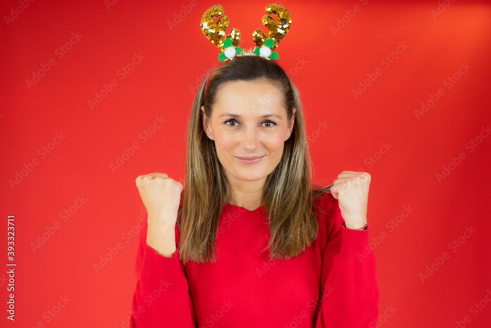 Close up photo of pretty woman making winner gesture wearing christmas clothes isolated over red background Close up photo of pretty woman making winner gesture wearing christmas clothes isolated over red background