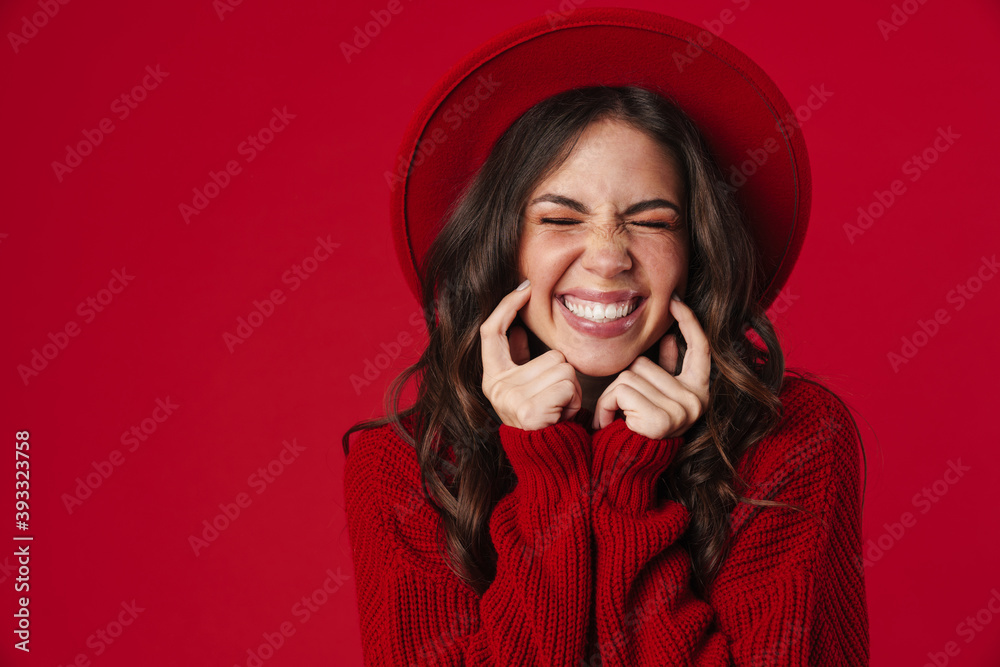 Joyful beautiful girl in hat pointing fingers at her cheeks and laughing Joyful beautiful girl in hat pointing fingers at her cheeks and laughing