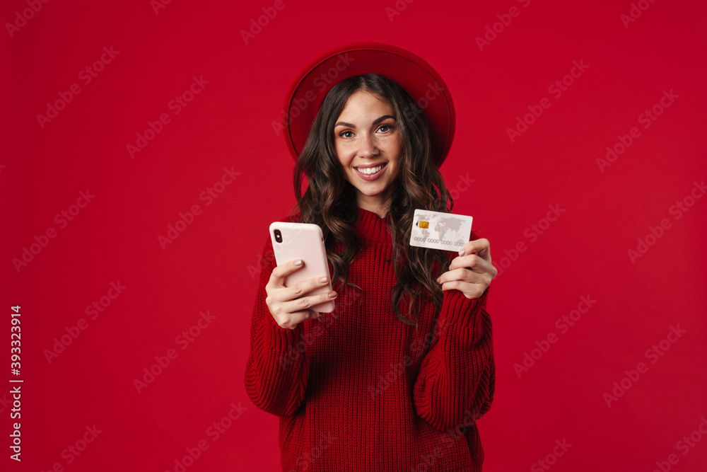 Happy beautiful brunette girl in hat holding cellphone and credit card Happy beautiful brunette girl in hat holding cellphone and credit card