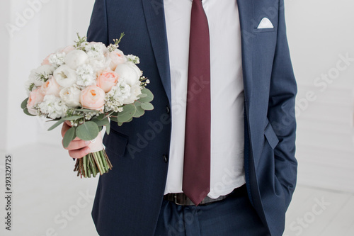 the groom at the wedding holds a bouquet of roses