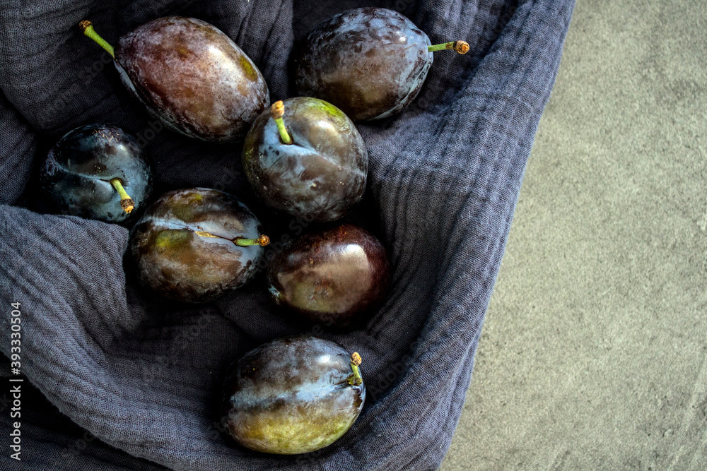 Fototapeta premium Plums on textured blue kitchen towel. Fresh summer fruits top view photo. Healthy eating concept. 