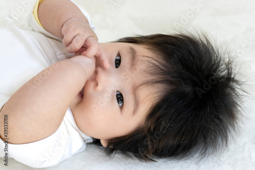 手を舐める赤ちゃんの顔（0歳、生後4か月、女の子）