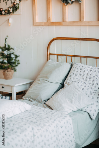 Old fashioned bed with many pillows. Rustic bedroom with christmas decorations. New year eve in the village.