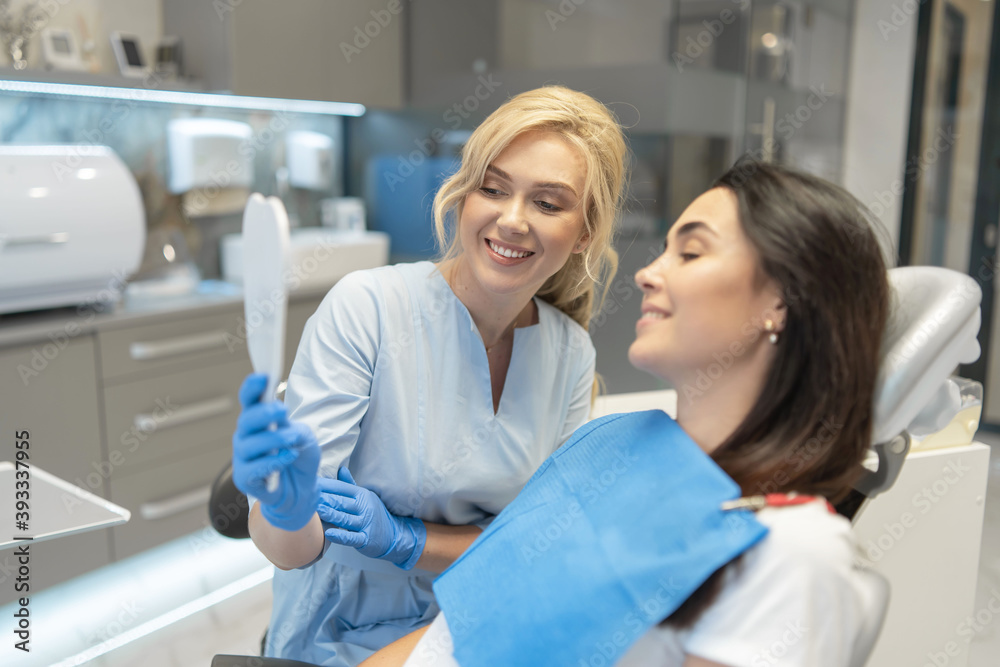 Female dentist in dental clinic providing examination and treatment of oral cavity for female patient. Female dentist in dental clinic providing examination and treatment of oral cavity for female patient.