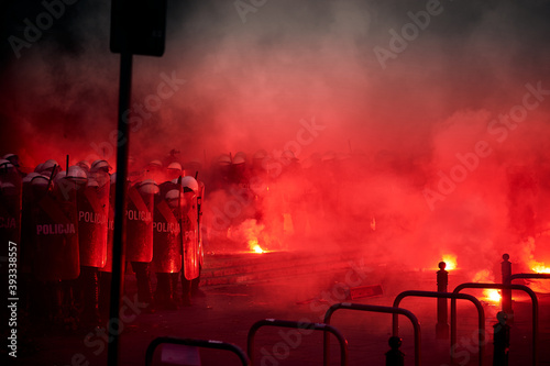 Police cordon and red flares during street protest