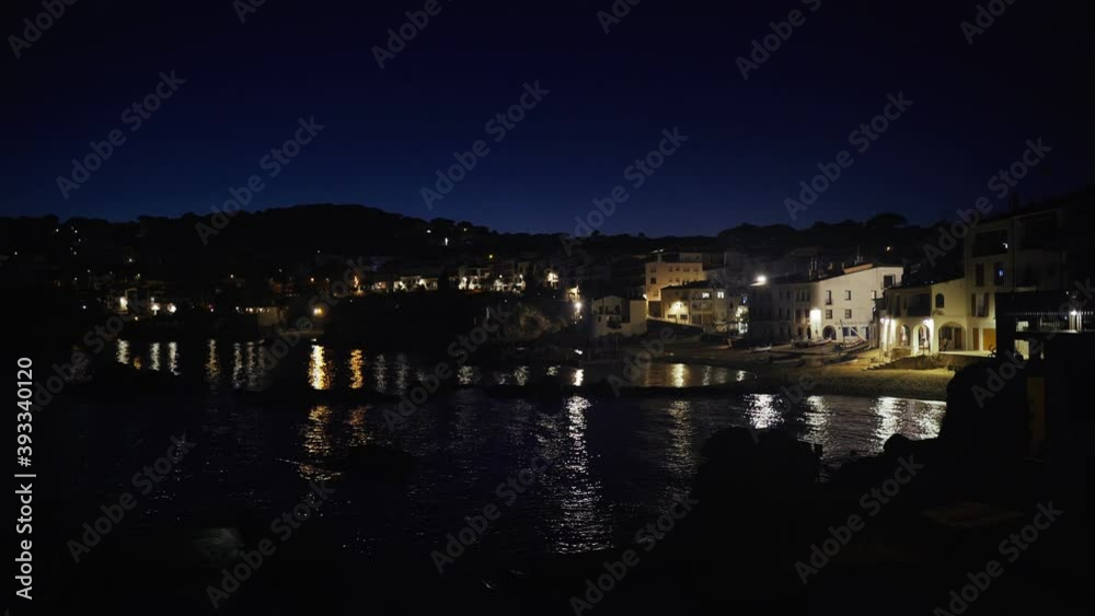 Beautiful Mediterranean village at evening. Night views on a small town on a sea coast. Water and lights of Calella de Palafrugell in Spain. Costa Brava vacation an chill. White houses on the beach.. Beautiful Mediterranean village at evening. Night views on a small town on a sea coast. Water and lights of Calella de Palafrugell in Spain. Costa Brava vacation an chill. White houses on the beach..