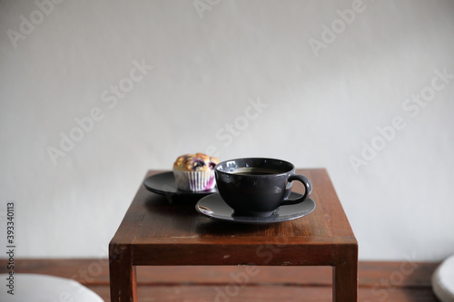 Coffee cup with muffin on wood table in local coffee shop