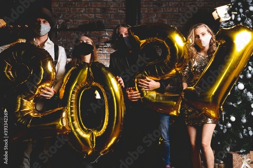 Corona virus pandemic. Party, people and new year holidays concept - women and men in protective medical mask celebrating new years eve 2021