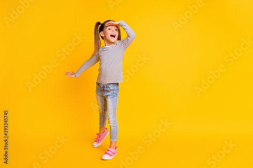 Full size photo of young smiling excited girl child kid hold hand on head look in distance copyspace isolated on yellow color background