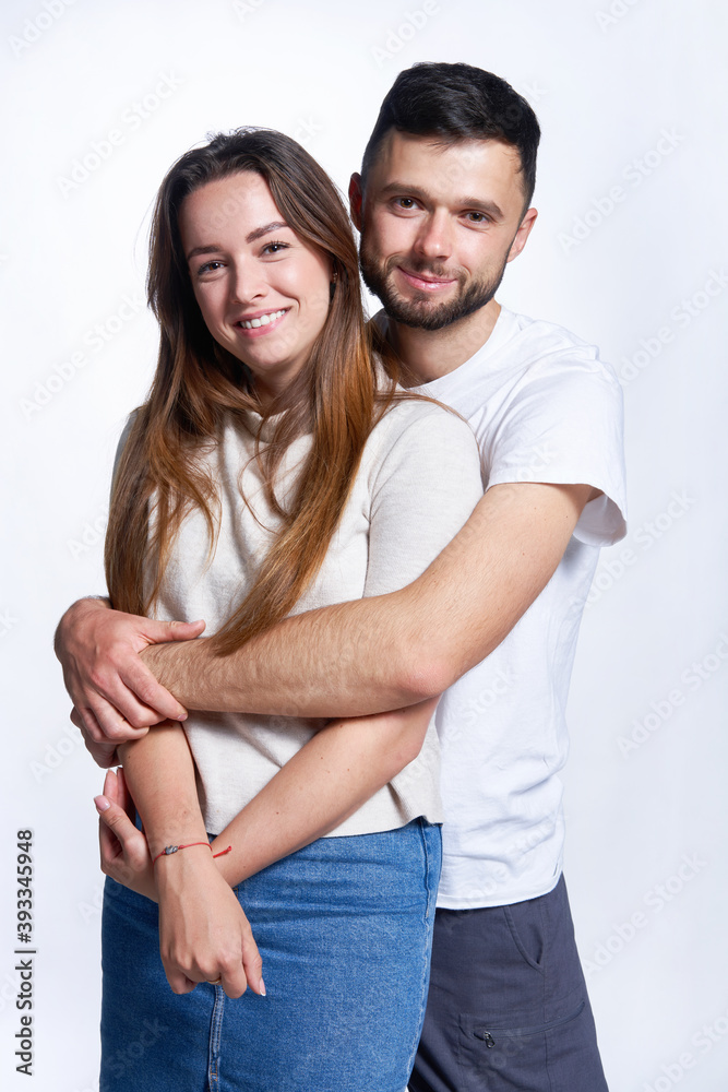 Smiling young couple hugging, studio portrait over light background Smiling young couple hugging, studio portrait over light background