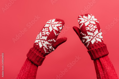 Fotografie cropped view of female hands in warm mittens isolated on red