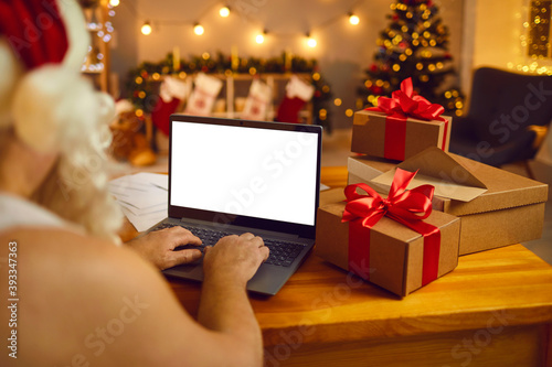 Funny Santa sitting typing Christmas New Year congratulation online on laptop photo