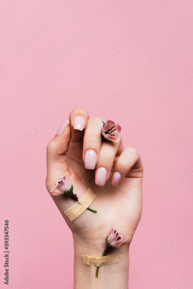 band aids with flowers on female hand isolated on pink