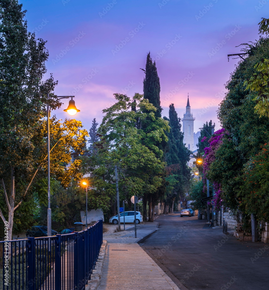 Beautiful dawn light on a quiet green street of Ein Karem neighborhood of Jerusalem, traditionaly believed to be the place of John the Baptist's birth; with a Catholic Church steeple in the distance Beautiful dawn light on a quiet green street of Ein Karem neighborhood of Jerusalem, traditionaly believed to be the place of John the Baptist's birth; with a Catholic Church steeple in the distance