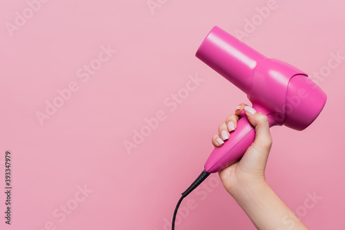 cropped view of woman holding hair dryer isolated on pink photo