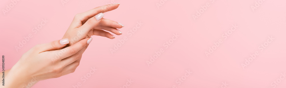 partial view of woman applying cosmetic cream on hands isolated on pink, banner partial view of woman applying cosmetic cream on hands isolated on pink, banner