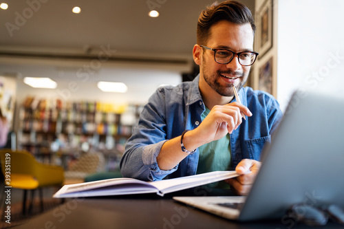 Smiling male student working and studying in a library photo