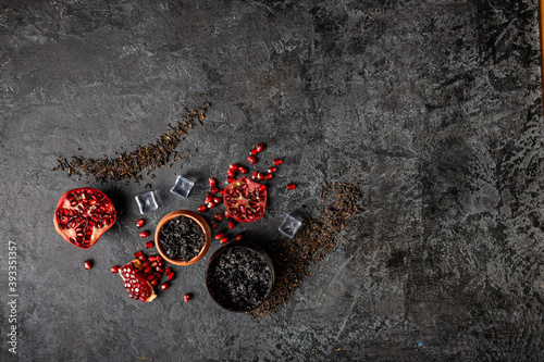 Top view or flat lay image of hookah tobacco. Hookah ceramic head fulled with aromated molose, pomegranade, blueberry and ice cubes on the grunge black table with smoke. photo