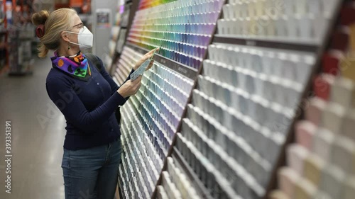 Woman wearing face mask looking at paint chips in a hardware store. Concept of cornonavirus shopping experience. photo