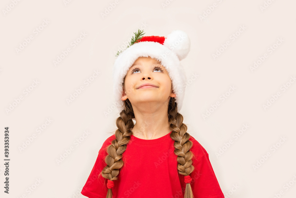 Beautiful little girl posing in a red t-shirt and Christmas hat. Beautiful little girl posing in a red t-shirt and Christmas hat.