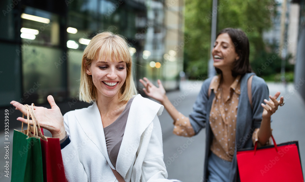 Beautiful young women with shopping bags on city street