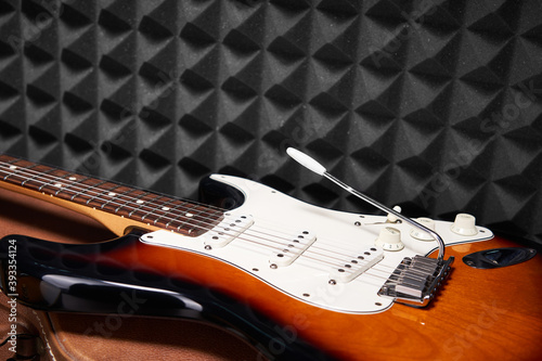 Sunburst electric guitar lying on acoustic foam panel background