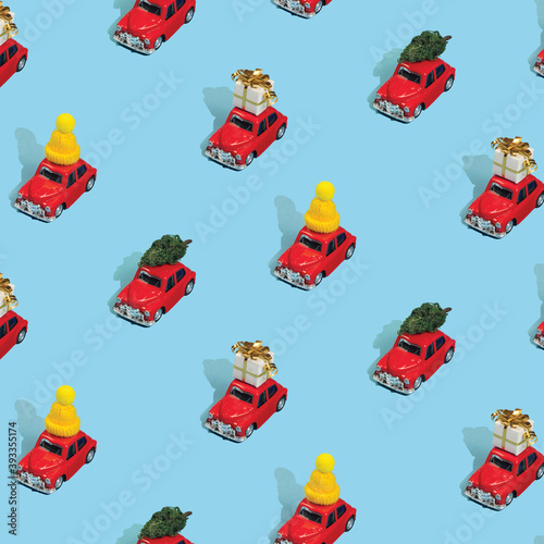 Christmas pattern made with New Year red cars with gifts, pine trees and hats on light blue background. Minimal Christmas concept.