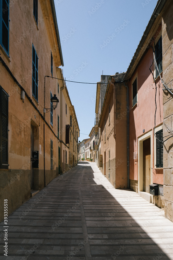 view of ground narrow street lane alley between houses with beautiful colours during summer in mallorca majorca