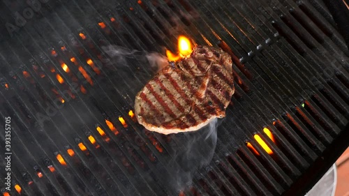 Flipping steaks on a barbecue with flames