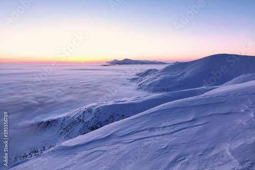 Winter. Awesome sunrise. High mountains with snow white peaks. A panoramic view of the covered with frost trees in the snowdrifts. Natural landscape with beautiful sky. The revival of the planet.
