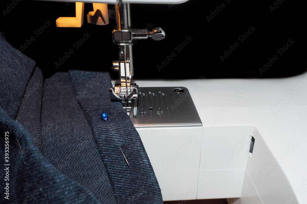 the process of shortening denim trousers on a white sewing machine on a
