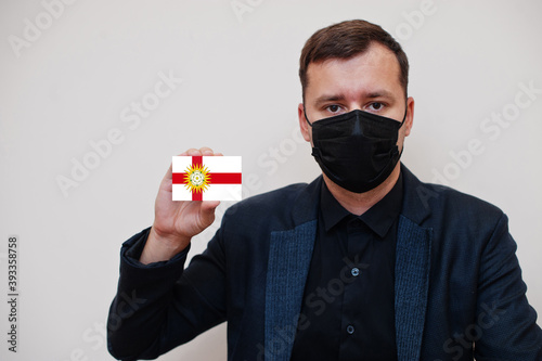 Man wear black formal and protect face mask, hold West Riding of Yorkshire flag card isolated on white background. United Kingdom counties of England coronavirus Covid concept. photo