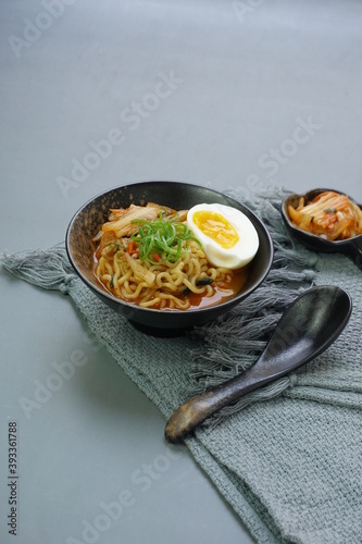Ramyeon or instant noodles soup from South Korea on black bowl. Served with Kimchi, eggs and leek