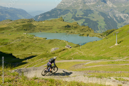Man on mountain bike going down the flow track from Jochpass over Engelberg in the Swiss Alps photo