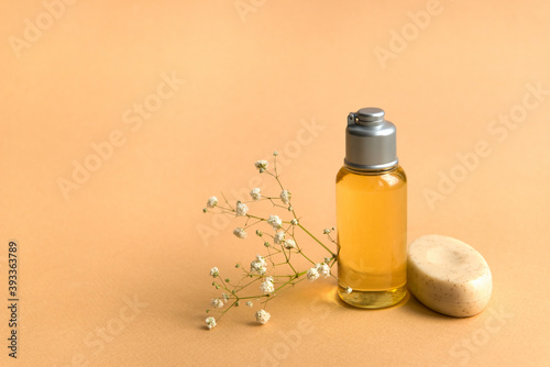Body care products - oil bottle and soap, gypsofila flowers on beige background photo