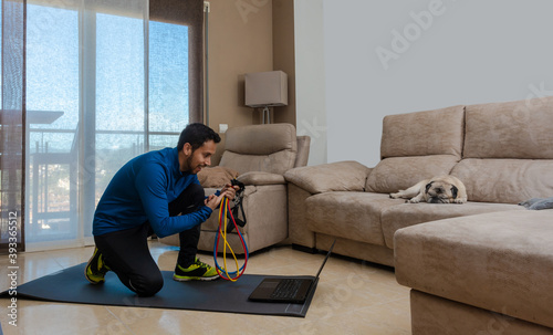 Latin man, doing a workout in his living room with a rubber band © expressiovisual
