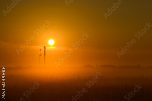 Foggy sunrise against the background of the Russian village