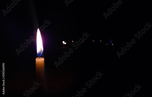 glowing candle flame in dark black background with copy space