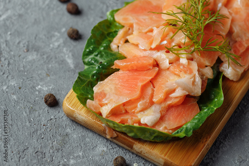 Pieces of fried salmon with dill and lemon wedges on a wooden board