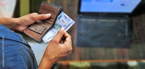 Young man taking Indian currency notes or banknotes out from wallet top view with copy space