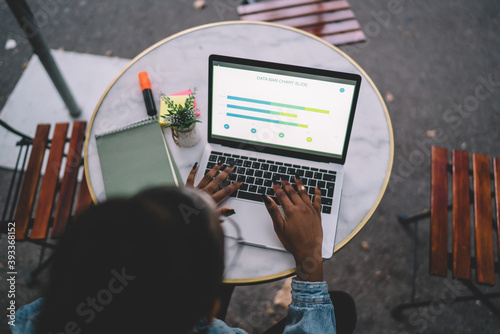 Photography Crop ethnic lady using laptop in outdoor cafe