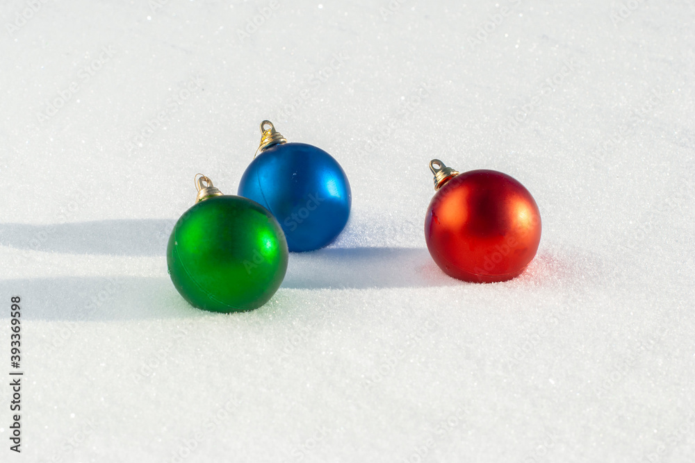 Christmas balls of green, red, blue colors lie in the snow. Close-up. Christmas balls of green, red, blue colors lie in the snow. Close-up.